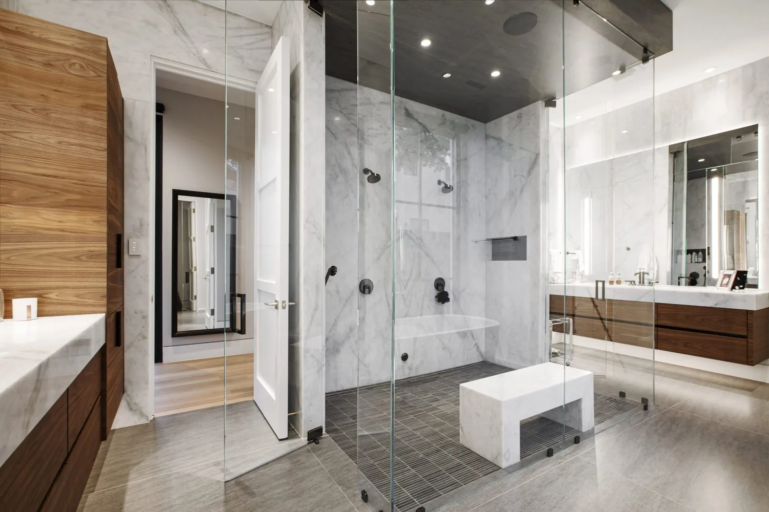 A marble wet room with a glass enclosure and a freestanding bench