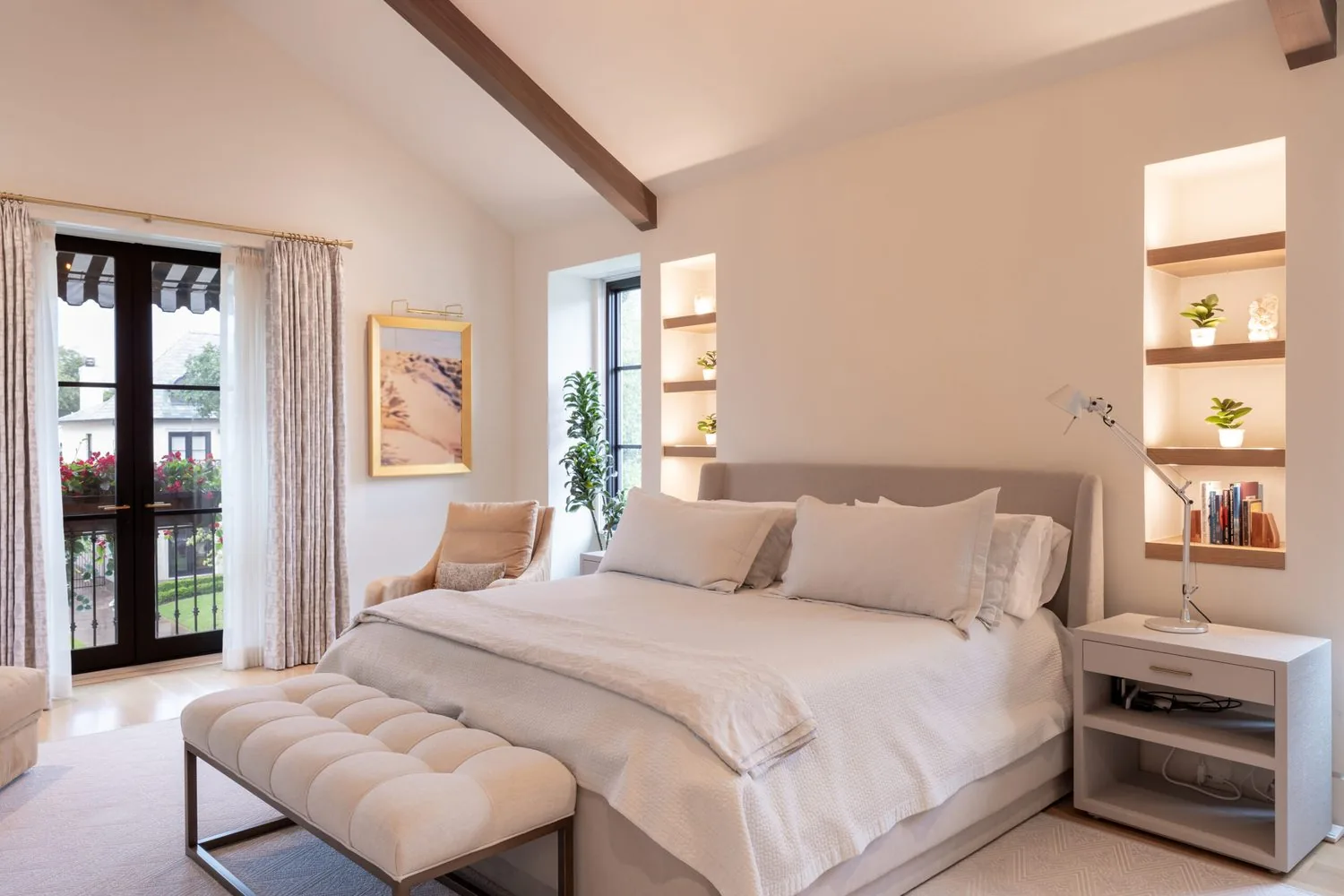 A vaulted primary bedroom with a bench at the foot of the bed