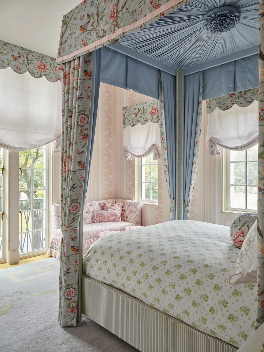 A canopy bed with printed hangings beneath a painted ceiling medallion