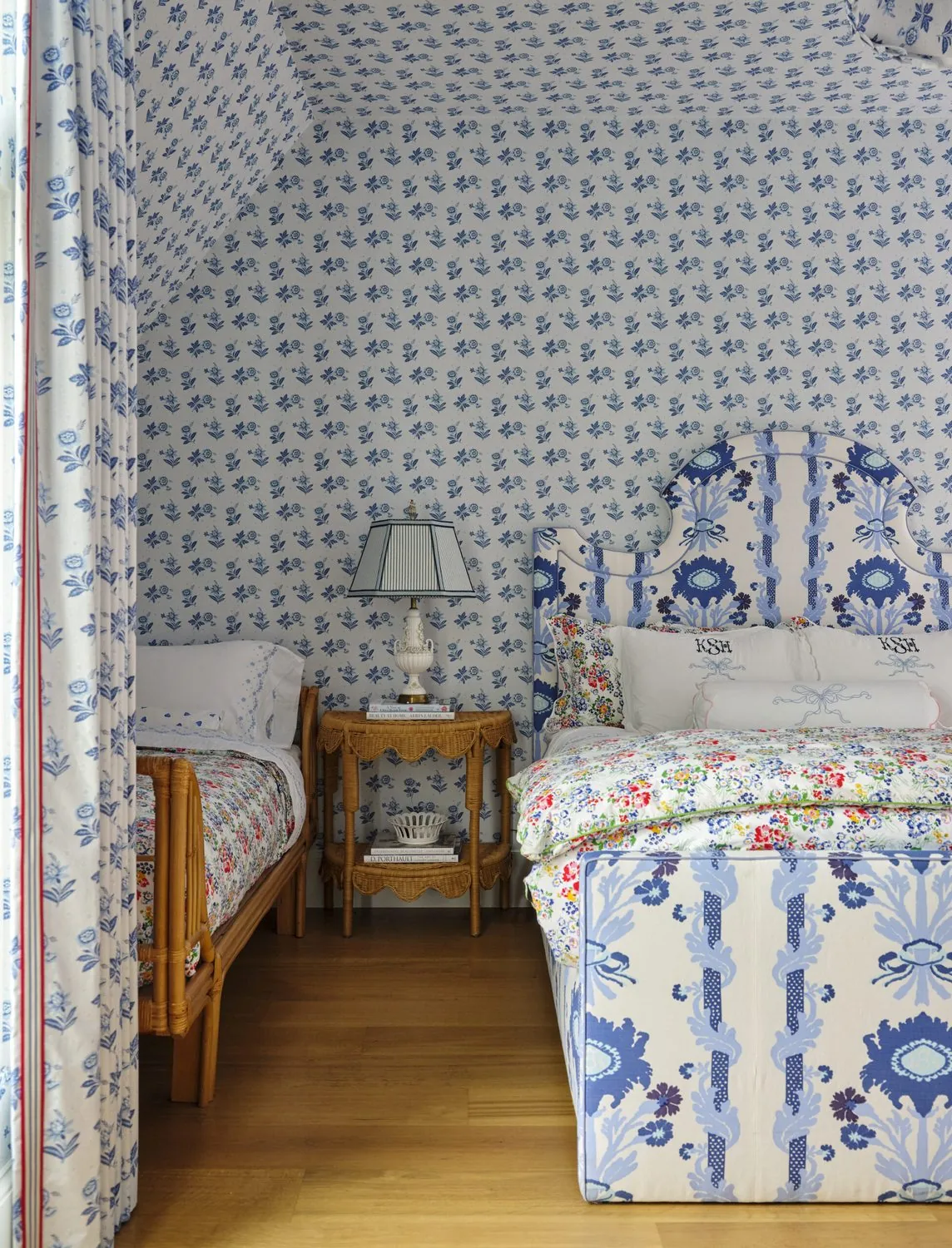 A bedroom papered in a blue print with matching bed hangings