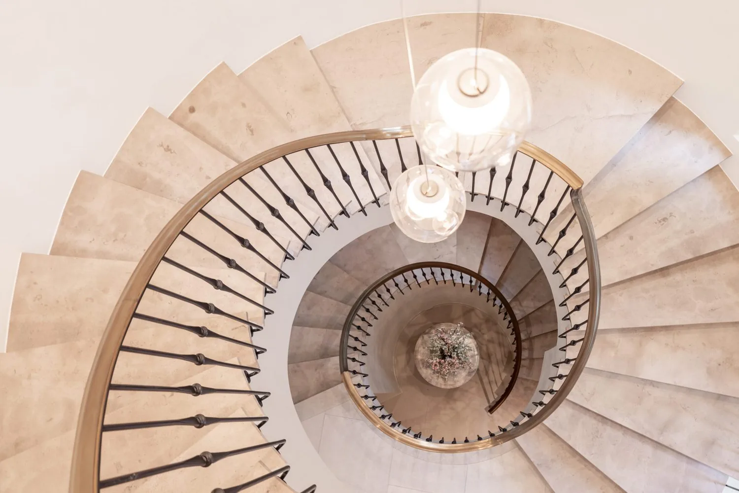 A stone spiral stair photographed from above with globe pendants