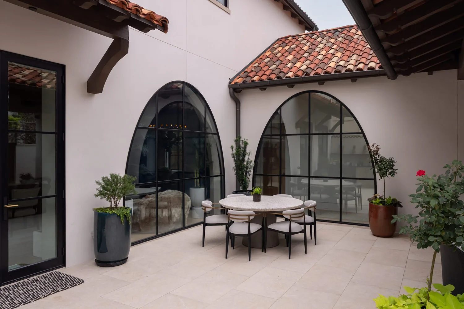 An arcaded loggia with iron doors and a round dining table