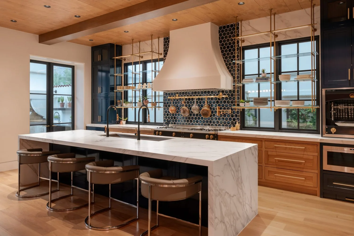 A kitchen with a plaster range hood, patterned tile and a long stone island
