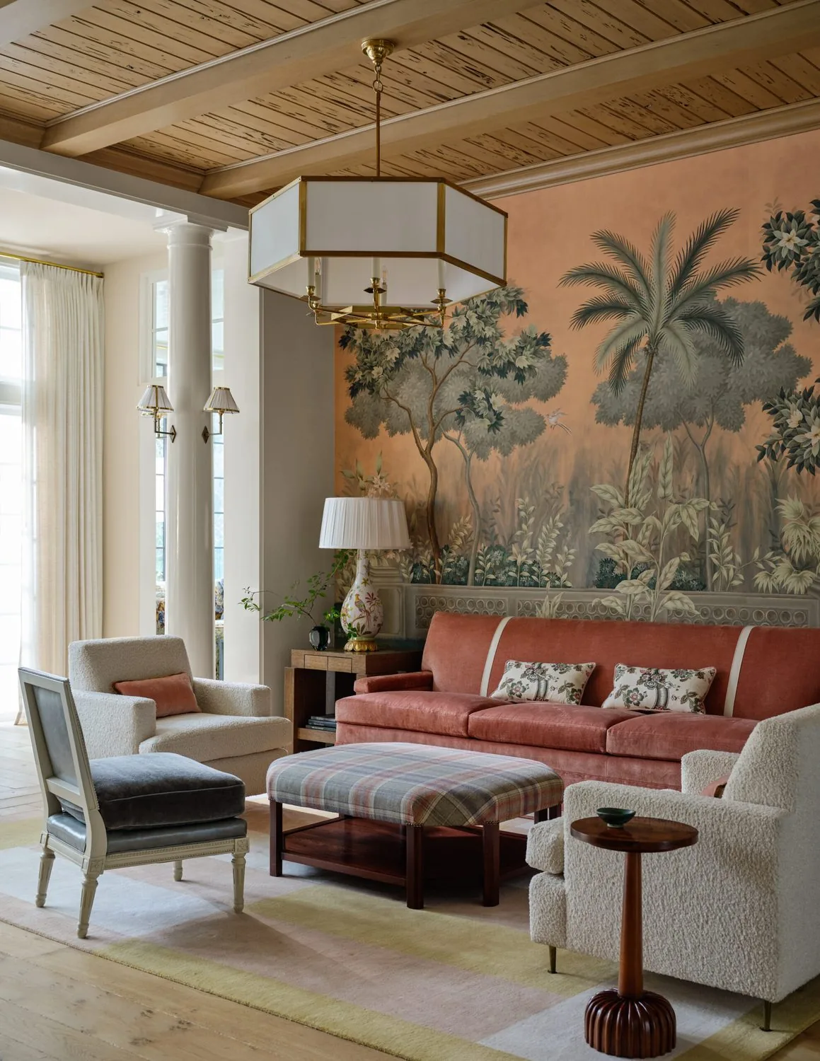 A sitting room with a hand-painted mural, coral sofa and boarded ceiling