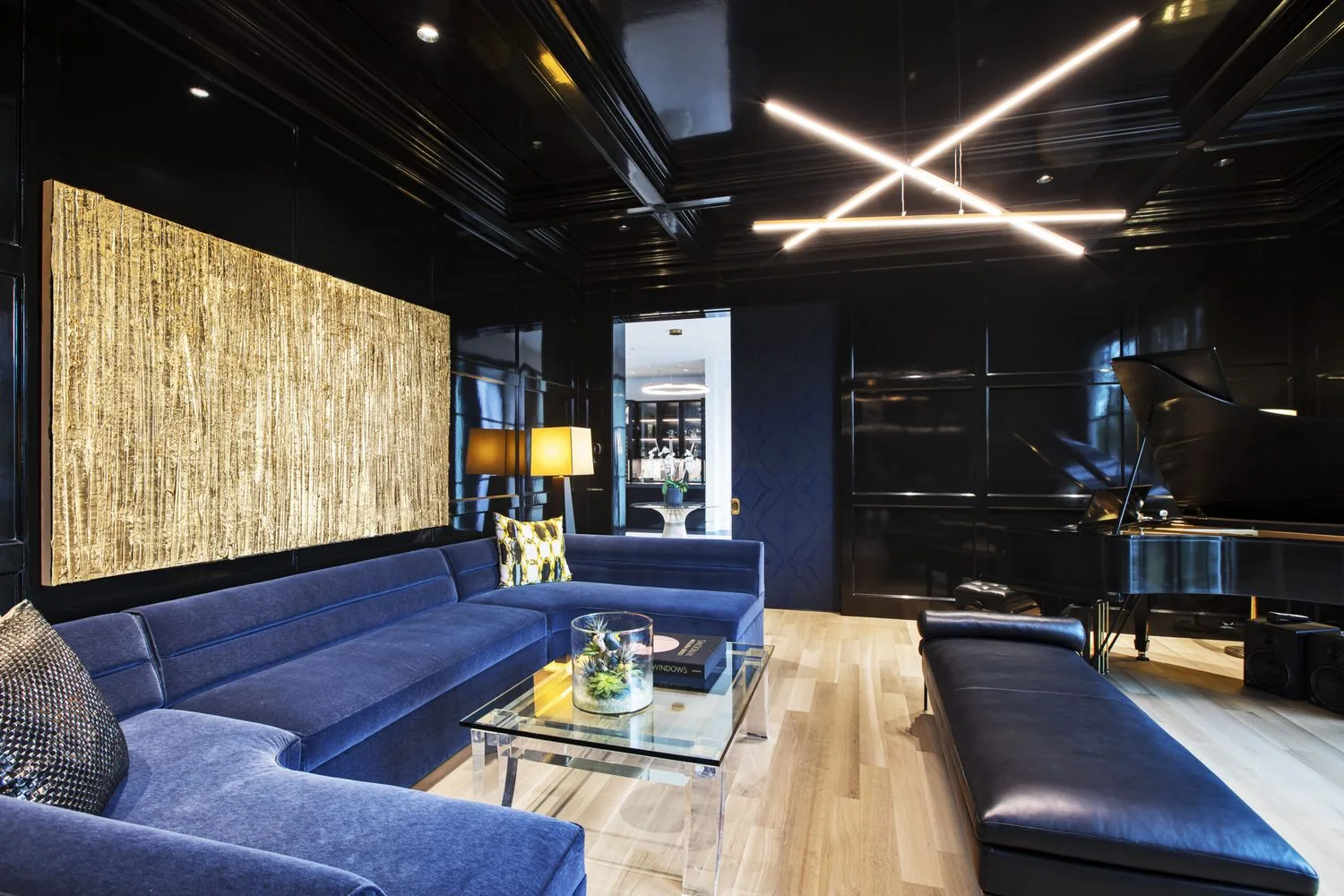 A media lounge in deep blue with a wraparound sectional and a lit ceiling