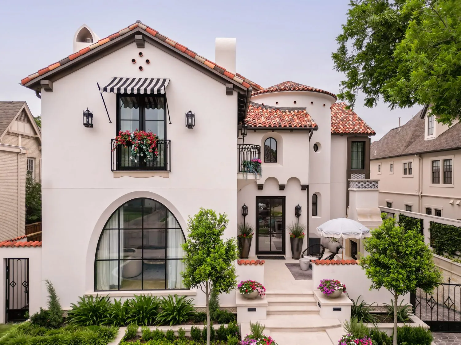 A stucco and clay-tile elevation with arched windows and iron balconies