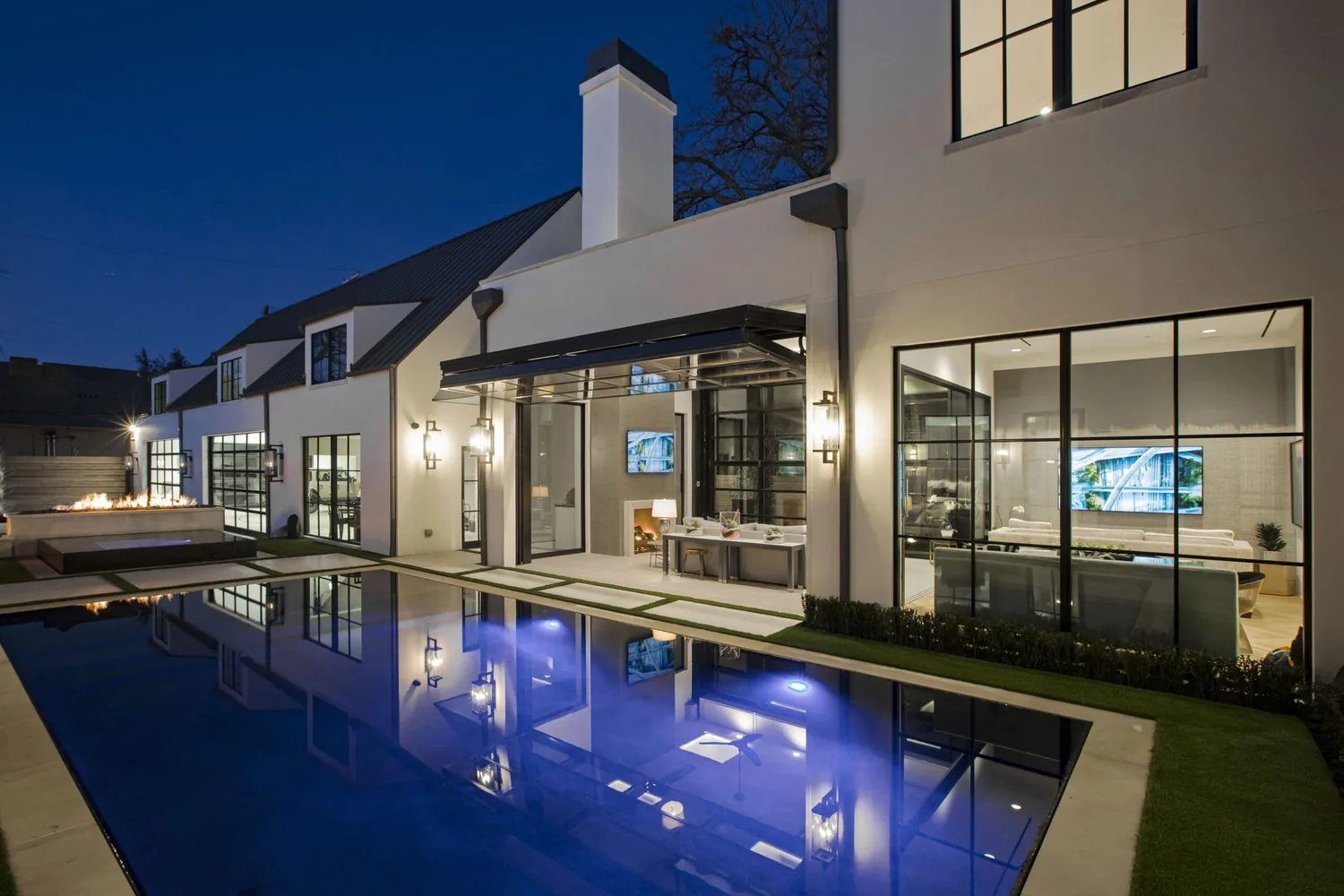 A University Park home at dusk with a long pool running alongside the rear elevation